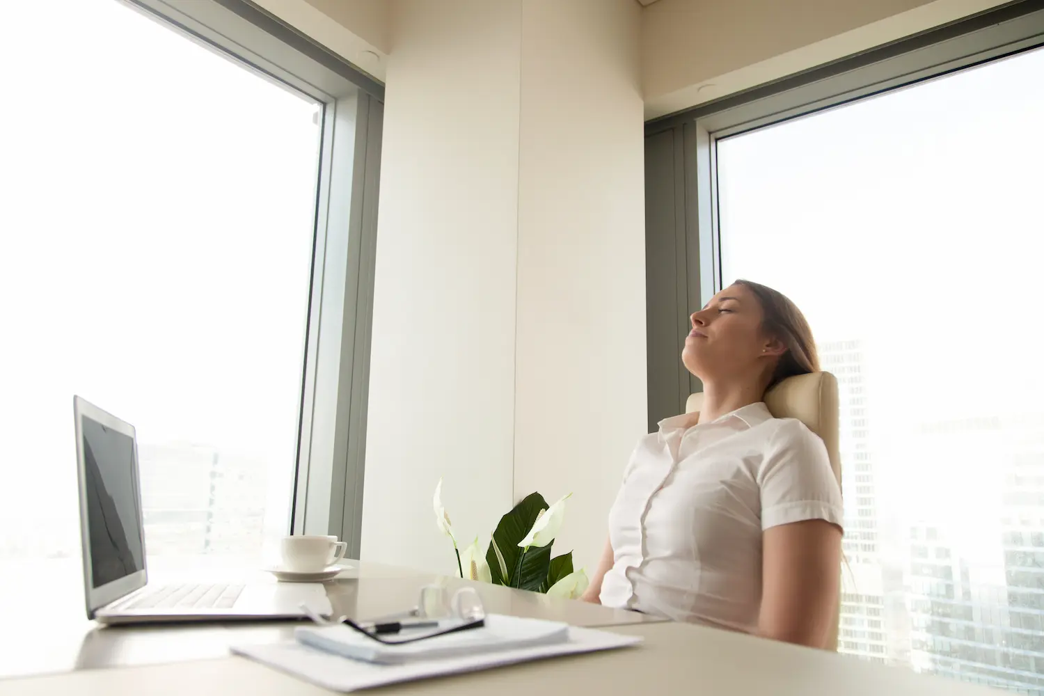 Remote worker taking a mindful breathing break at their desk, eyes closed and hands resting on lap