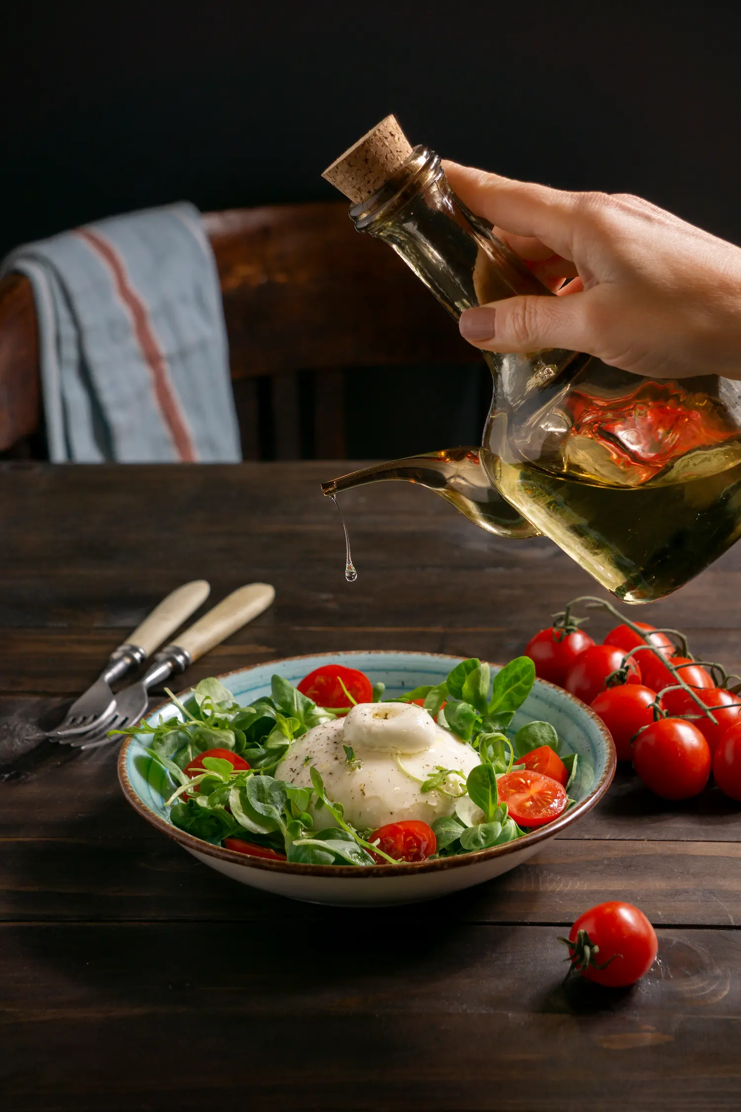A small mason jar of homemade dressing with herbs around it