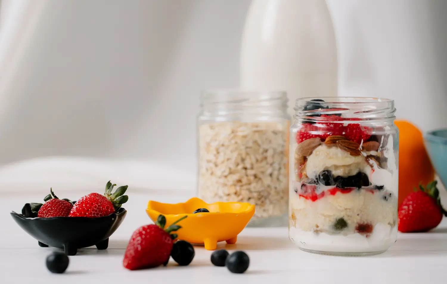 Two jars of oats with fruit stacked in a fridge door