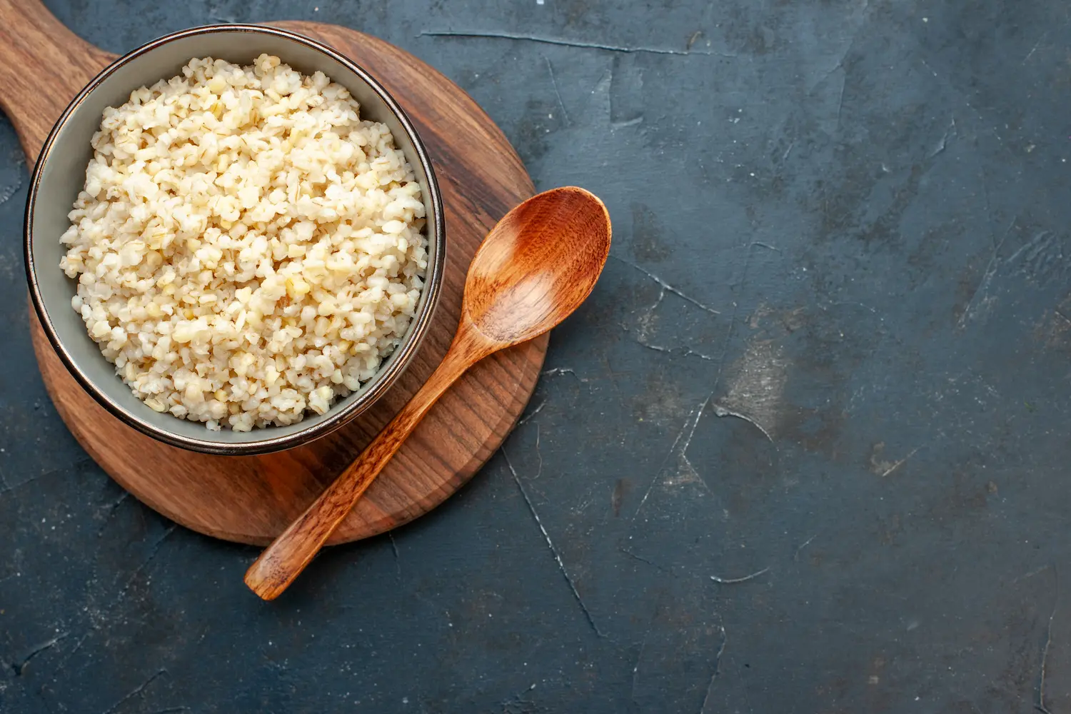 A glass container of cooked quinoa next to a lunchbox